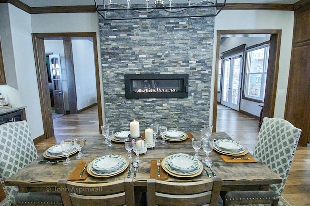 dining room with hardwood / wood-style flooring, french doors, ornamental molding, and a fireplace