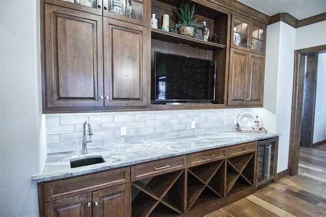 bar featuring light stone counters, sink, beverage cooler, and tasteful backsplash