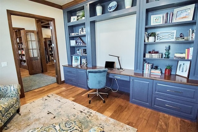 office area featuring built in shelves, hardwood / wood-style floors, and crown molding