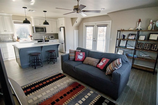 living room featuring sink, ceiling fan, and french doors