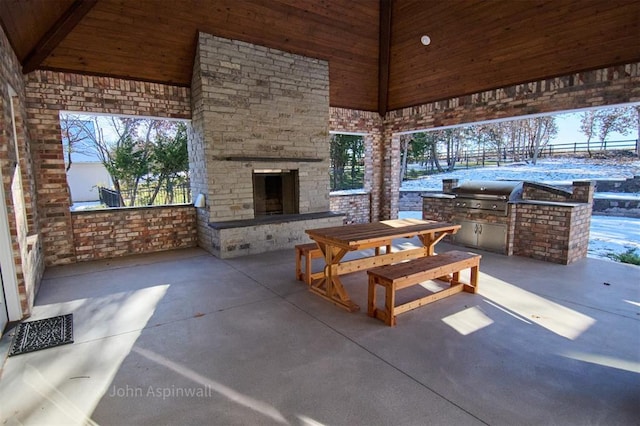 view of patio with exterior kitchen, an outdoor stone fireplace, and area for grilling