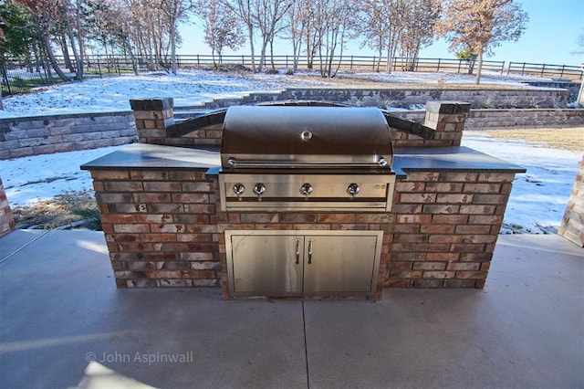 snow covered patio with an outdoor kitchen and grilling area