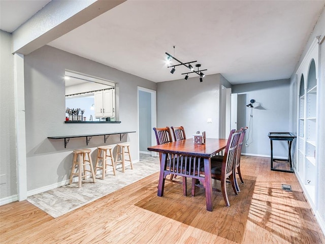 dining space with light wood-type flooring, a chandelier, and rail lighting