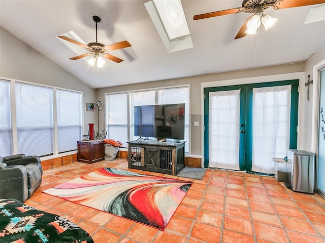 living room with ceiling fan, french doors, lofted ceiling with skylight, and light tile patterned flooring