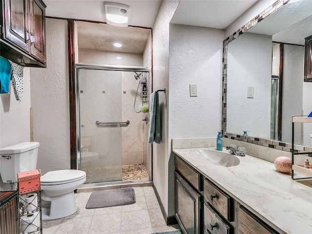 bathroom featuring toilet, vanity, and a shower with shower door