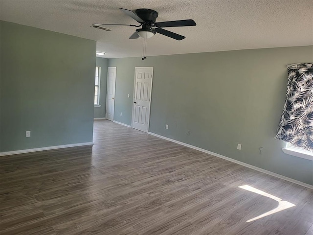 empty room featuring ceiling fan, wood-type flooring, and a textured ceiling