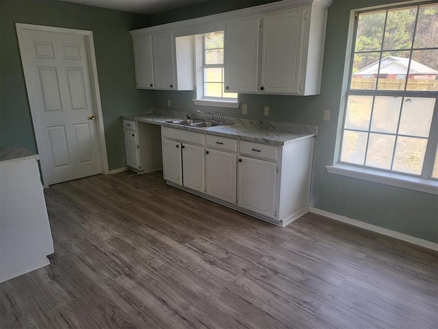 kitchen with a wealth of natural light, light hardwood / wood-style floors, white cabinets, and sink