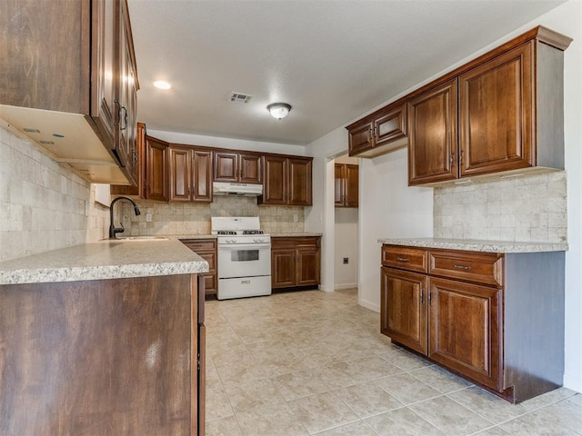 kitchen with light tile patterned floors, gas range gas stove, decorative backsplash, and sink