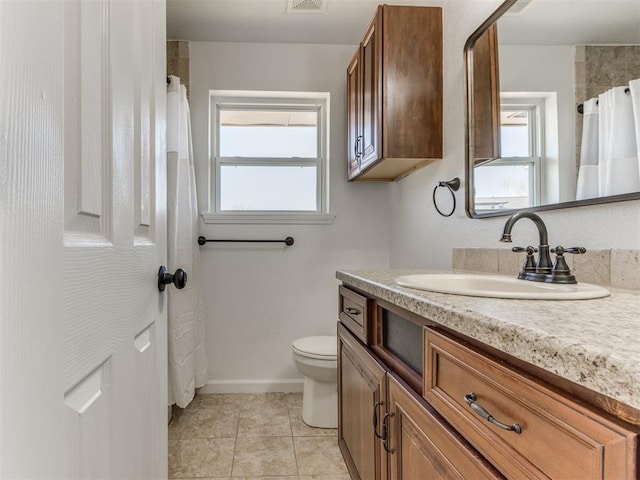 bathroom with a wealth of natural light, toilet, vanity, and tile patterned flooring