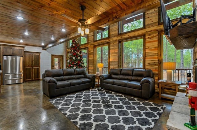 living room with ceiling fan, wooden walls, wooden ceiling, and a towering ceiling