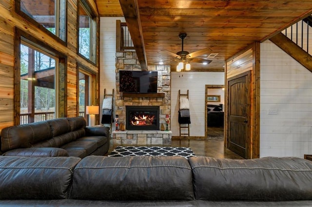 living room with a fireplace, a towering ceiling, wood ceiling, ceiling fan, and wooden walls