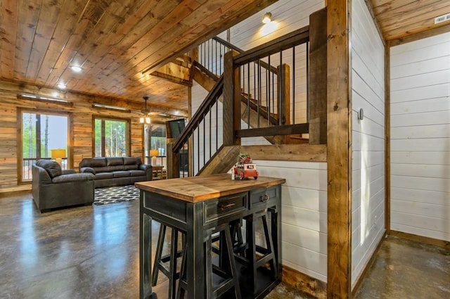 interior space with concrete floors, wood ceiling, and wood walls