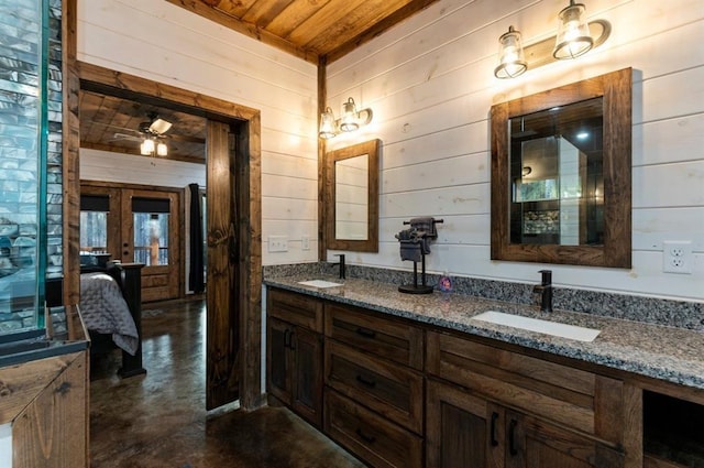 bathroom featuring wooden ceiling, vanity, concrete flooring, and wooden walls