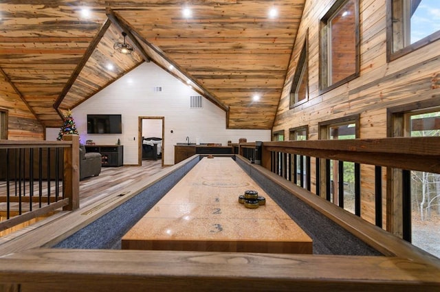 recreation room with high vaulted ceiling, wooden ceiling, and wood walls