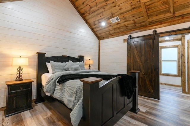 bedroom with light wood-type flooring, lofted ceiling, a barn door, wood walls, and wooden ceiling