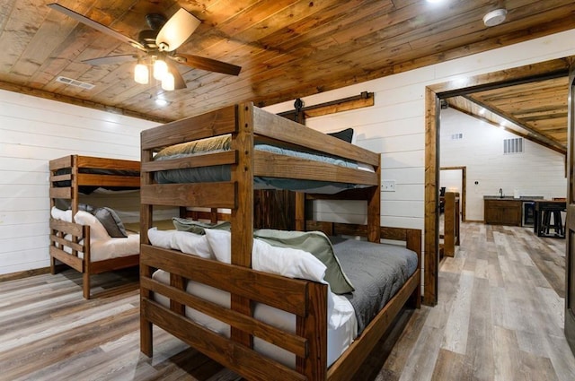 bedroom featuring light hardwood / wood-style flooring, wood walls, and wood ceiling