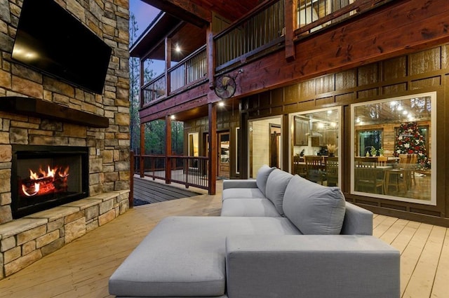 living room featuring wood-type flooring, wood walls, and an outdoor stone fireplace