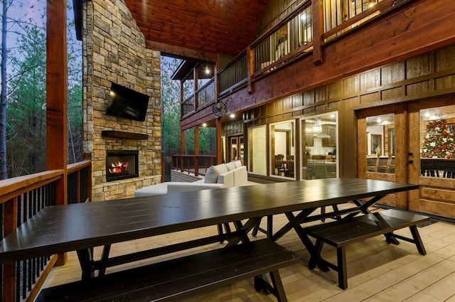 dining space with an outdoor stone fireplace, light hardwood / wood-style floors, french doors, and wooden ceiling