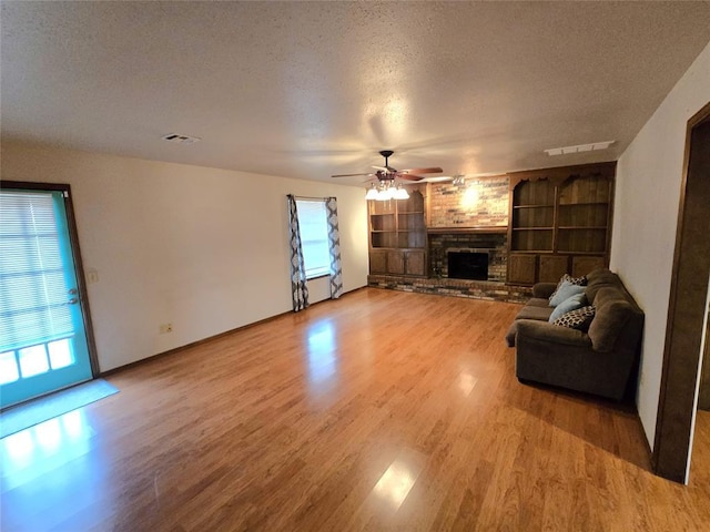 unfurnished living room with ceiling fan, a fireplace, hardwood / wood-style floors, and a textured ceiling