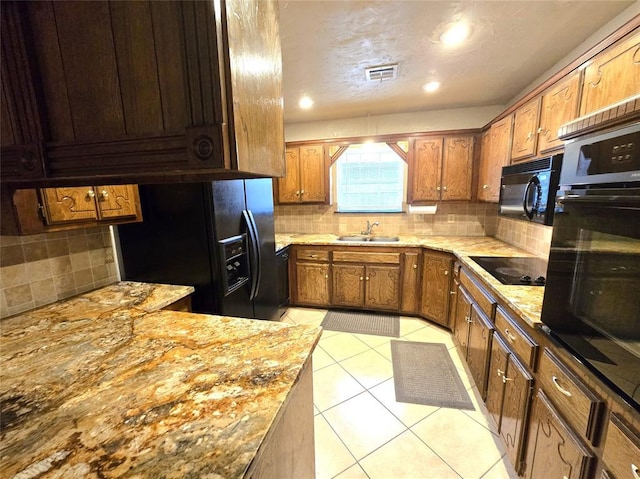 kitchen featuring tasteful backsplash, sink, light tile patterned floors, light stone counters, and black appliances