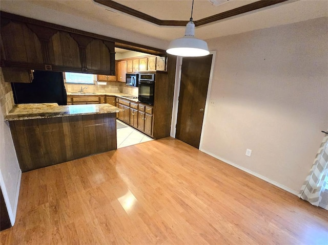 kitchen featuring kitchen peninsula, sink, backsplash, light hardwood / wood-style floors, and black appliances