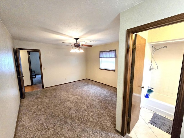 carpeted spare room featuring ceiling fan and a textured ceiling