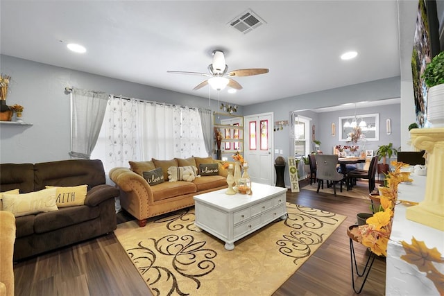 living room with ceiling fan with notable chandelier and light hardwood / wood-style flooring