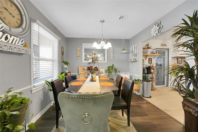 dining area with dark wood-type flooring and an inviting chandelier