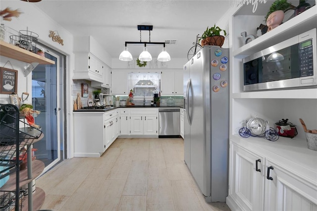 kitchen featuring stainless steel appliances, white cabinets, backsplash, and pendant lighting