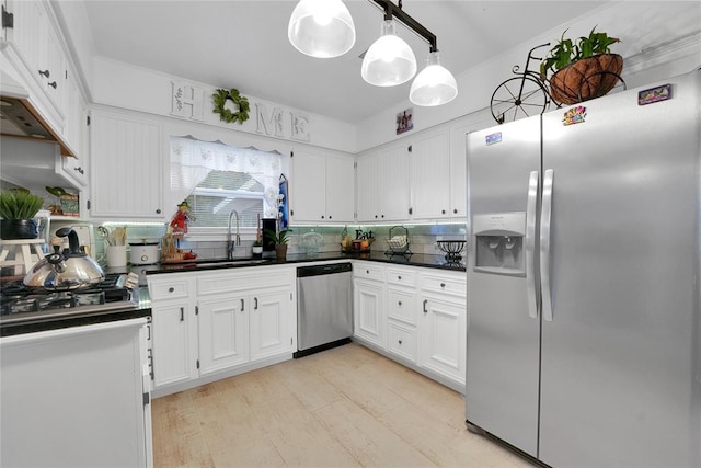 kitchen with appliances with stainless steel finishes, hanging light fixtures, white cabinetry, and sink