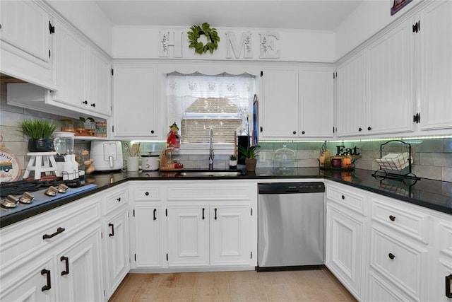 kitchen featuring appliances with stainless steel finishes, white cabinetry, tasteful backsplash, and sink