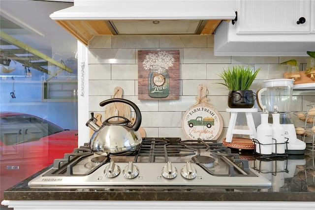 room details featuring white cabinets, extractor fan, stainless steel gas cooktop, and tasteful backsplash