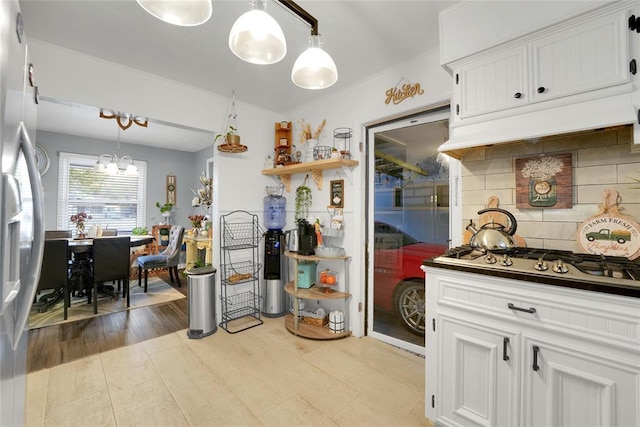 kitchen featuring decorative light fixtures, stainless steel appliances, white cabinetry, and decorative backsplash