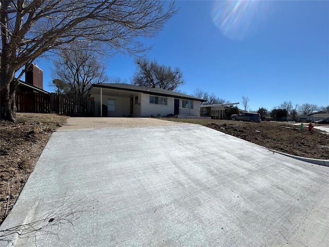 ranch-style house with concrete driveway, a carport, and fence