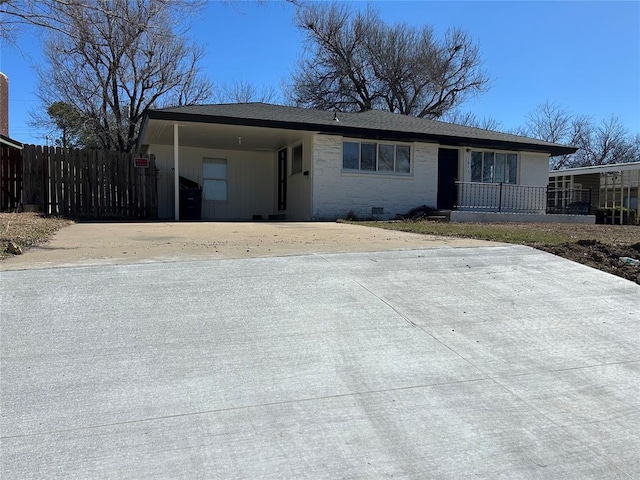 ranch-style home with concrete driveway, an attached carport, crawl space, fence, and brick siding