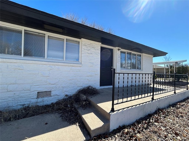 entrance to property featuring crawl space and fence