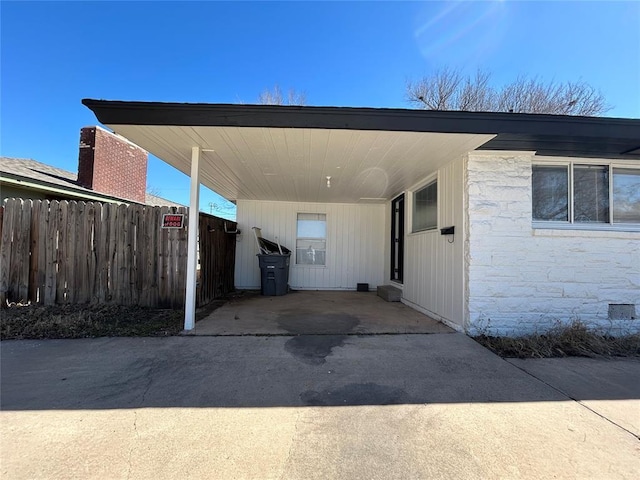 view of vehicle parking featuring an attached carport and fence