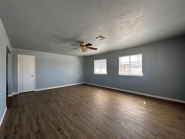 spare room with a ceiling fan, baseboards, visible vents, and dark wood-style flooring