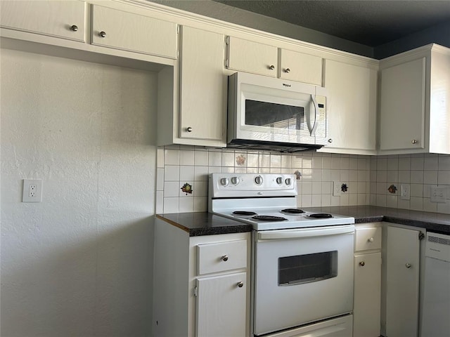 kitchen featuring dark countertops, white appliances, and backsplash