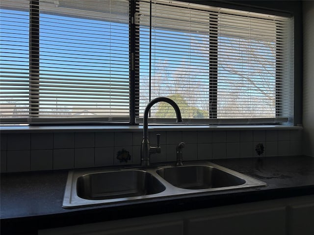 kitchen featuring dark countertops, a sink, and decorative backsplash