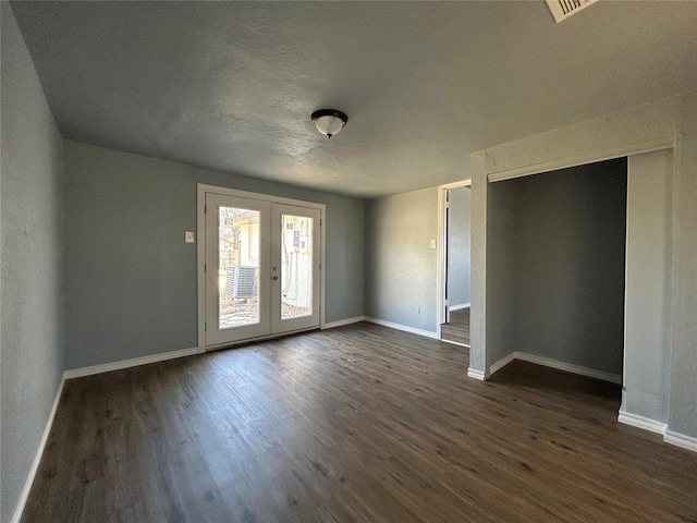 unfurnished room with dark wood-style floors, french doors, visible vents, and baseboards