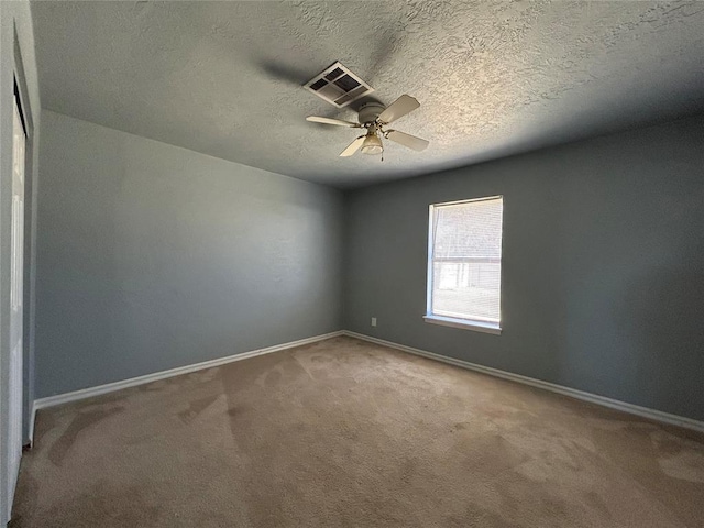 empty room featuring carpet floors, visible vents, baseboards, and ceiling fan