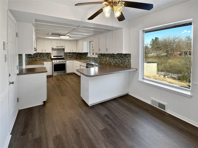 kitchen featuring ceiling fan, kitchen peninsula, white cabinetry, dark wood-type flooring, and gas range