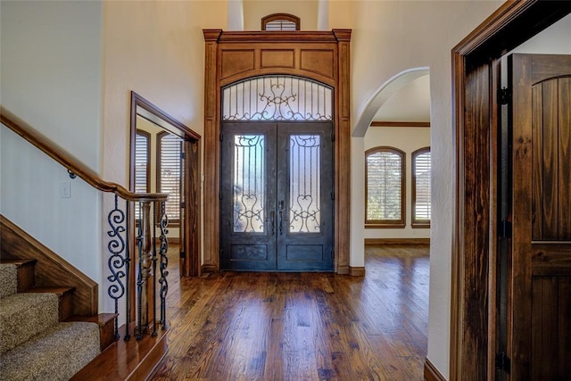 foyer entrance with french doors, dark hardwood / wood-style flooring, a high ceiling, and ornamental molding