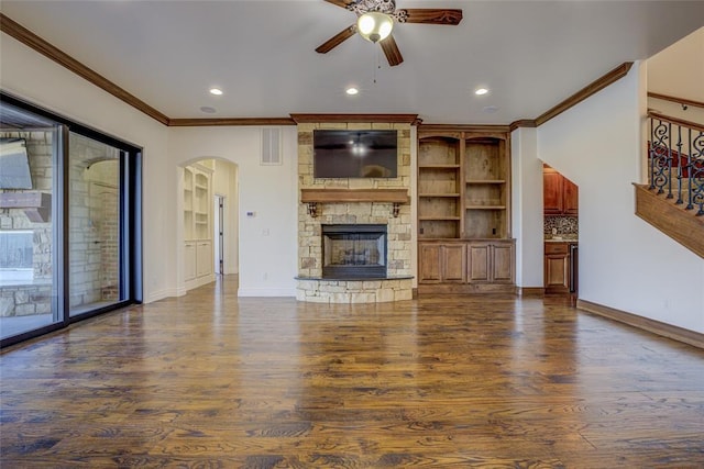 unfurnished living room with ceiling fan, dark wood-type flooring, ornamental molding, and a fireplace