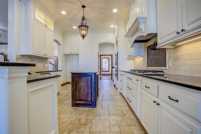 kitchen with white cabinetry, dark stone countertops, hanging light fixtures, and custom range hood