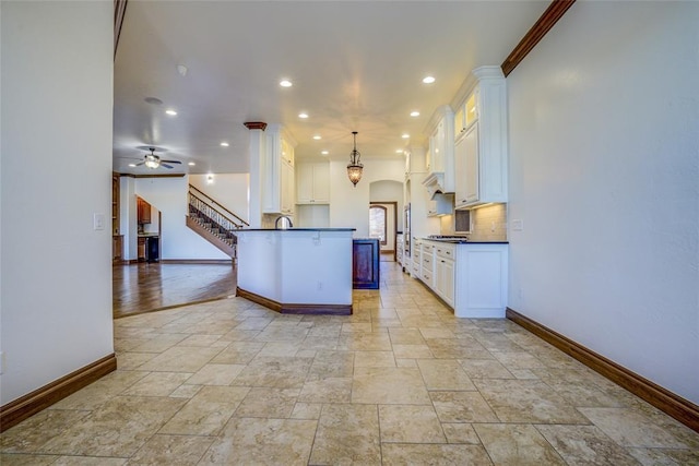 kitchen featuring decorative light fixtures, white cabinetry, crown molding, and ceiling fan