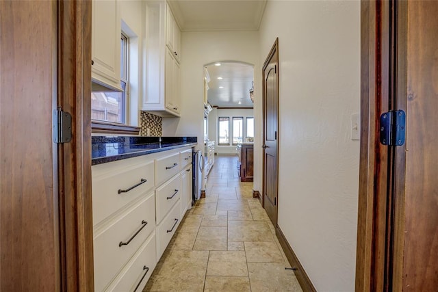 kitchen with ornamental molding, dark stone countertops, white cabinets, and tasteful backsplash