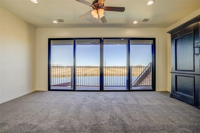 unfurnished room featuring ceiling fan, a healthy amount of sunlight, a water view, and carpet floors