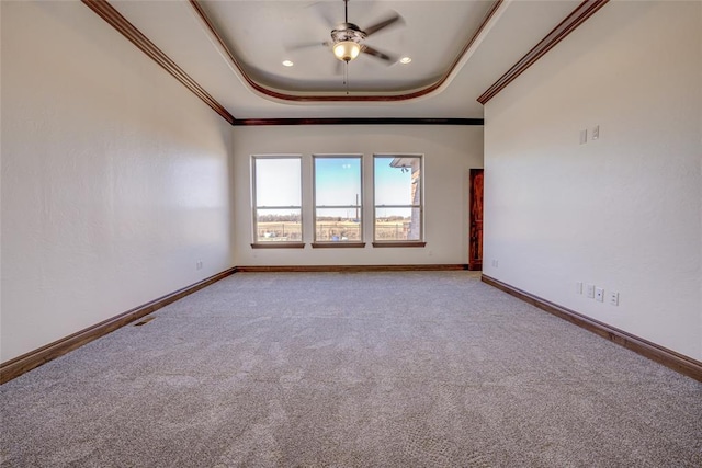 carpeted empty room featuring crown molding, ceiling fan, and a tray ceiling